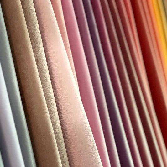 Colorful goat leather hides displayed in gradient shades, premium chèvre leather for luxury bags, wallets, and fine leathercraft projects.